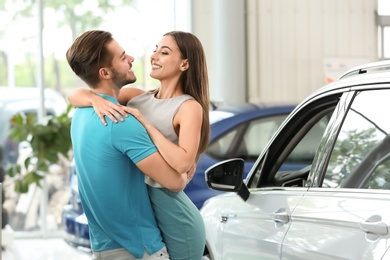 Photo of Happy couple buying new car in salon