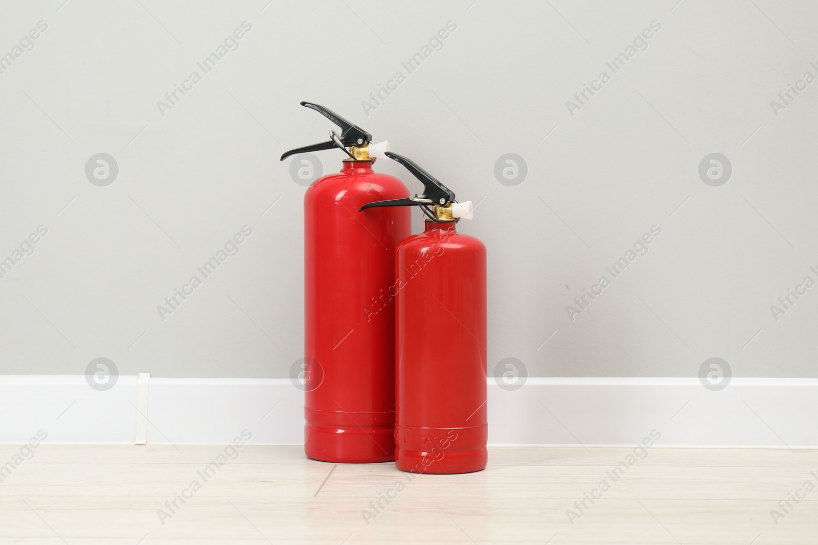 Photo of Fire extinguishers on floor near light grey wall