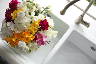 Beautiful bouquet with fresh freesia flowers in kitchen sink, above view