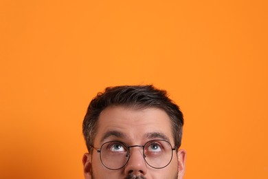 Photo of Man in stylish glasses on orange background, closeup