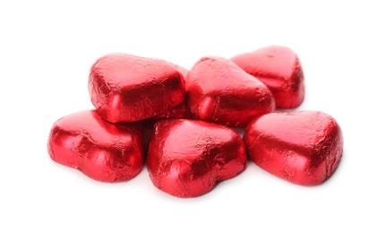 Photo of Heart shaped chocolate candies in red foil on white background