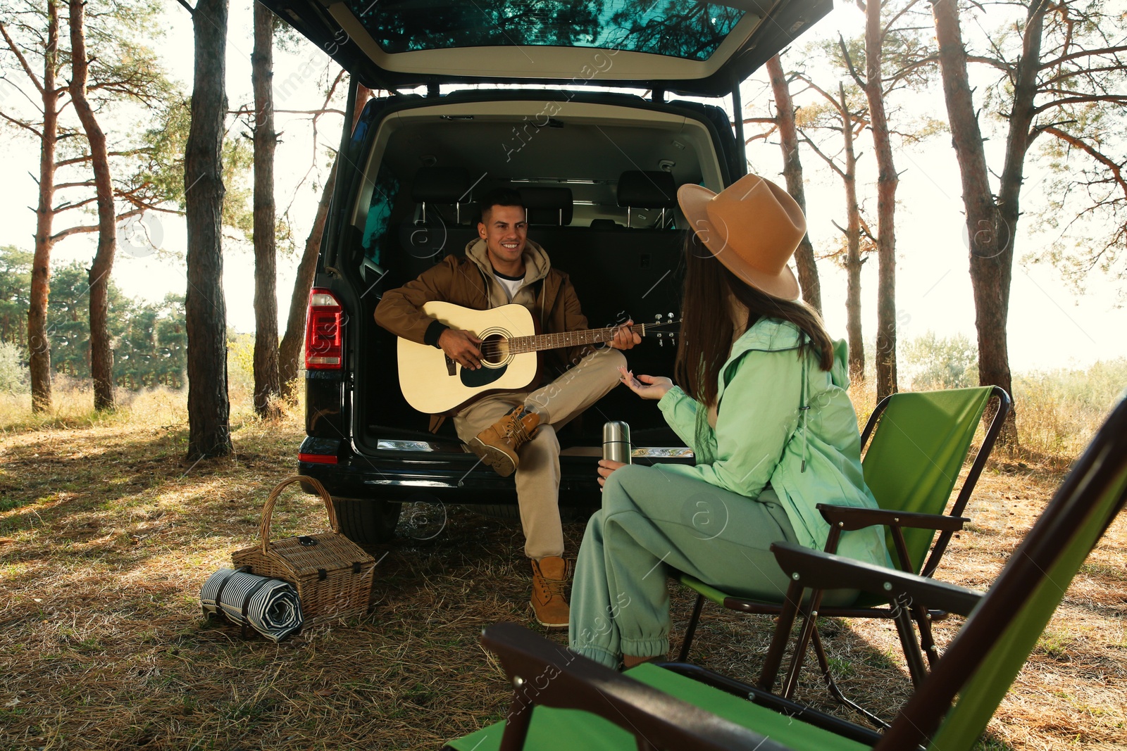 Photo of Couple with guitar, picnic basket and chairs at camping site