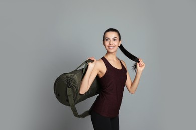 Beautiful woman with sports bag on grey background