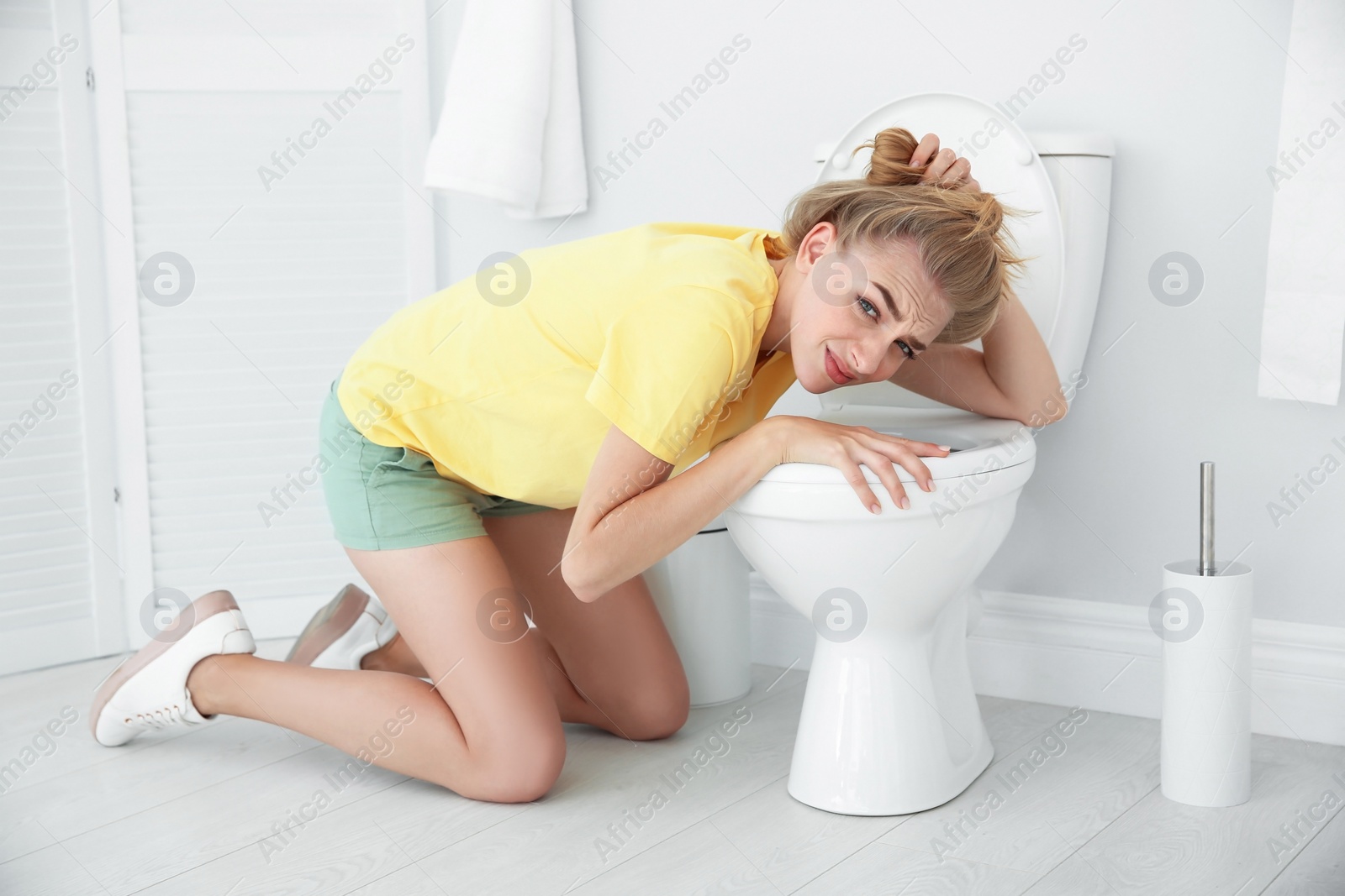 Photo of Young woman vomiting in toilet bowl at home