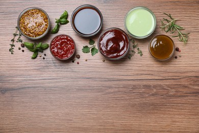 Photo of Many different sauces on wooden table, flat lay. Space for text