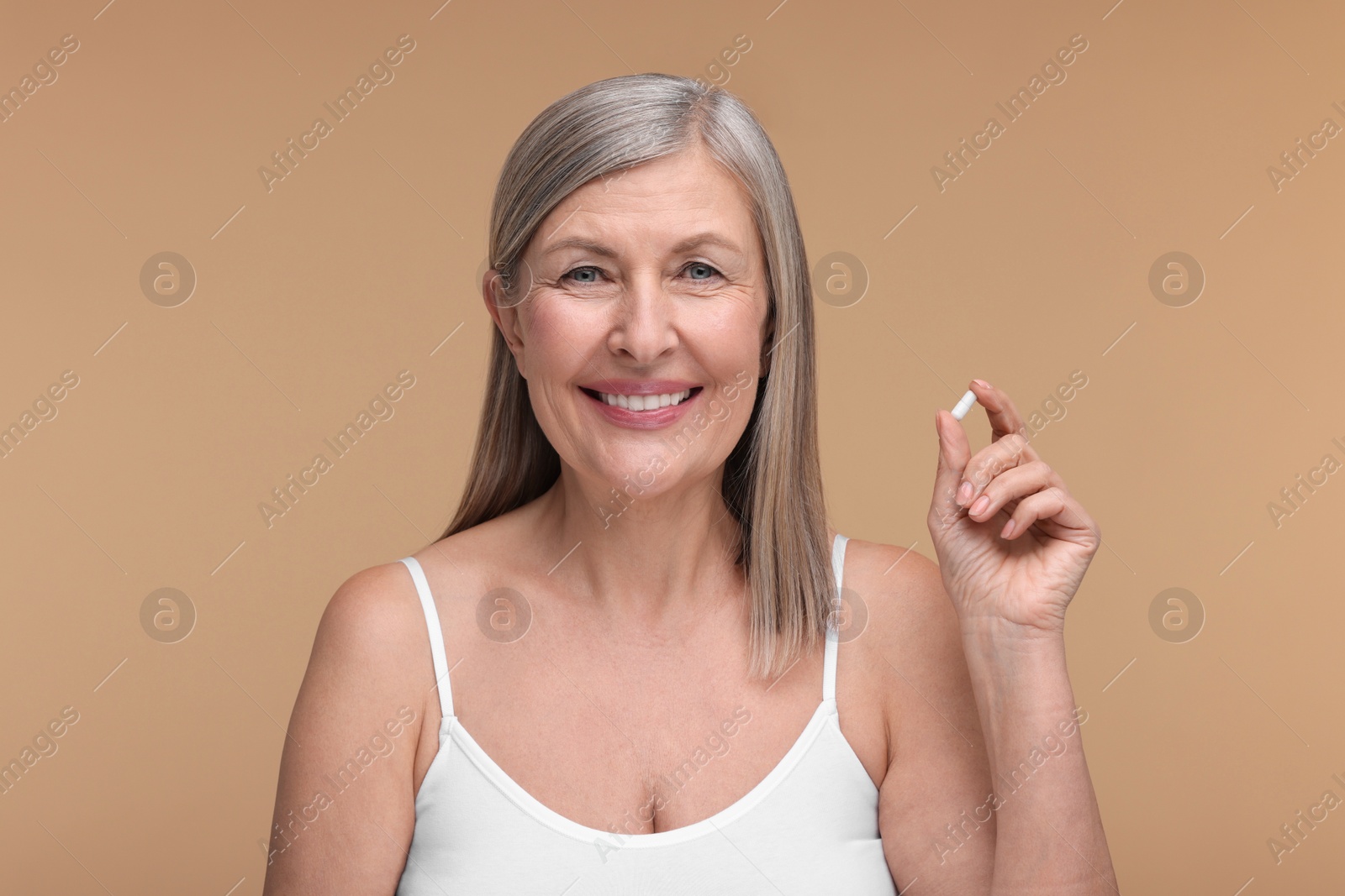 Photo of Beautiful woman with vitamin capsule on beige background