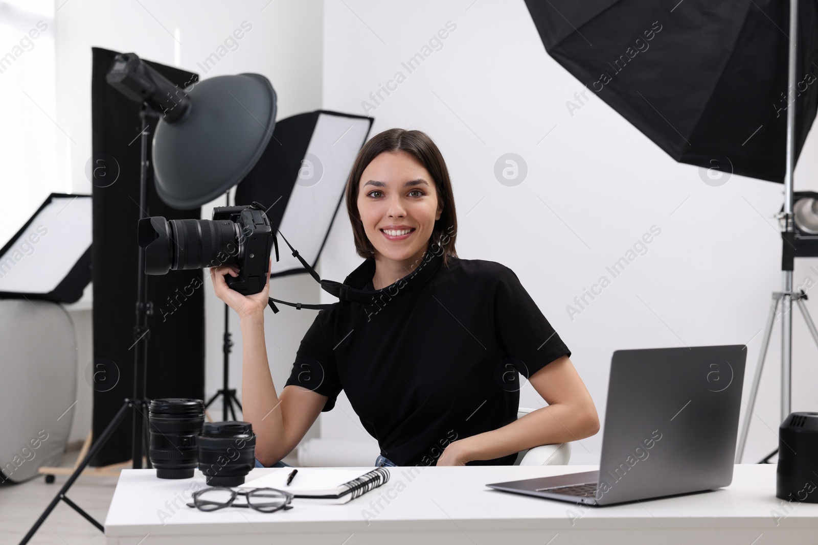 Photo of Young professional photographer with camera at table in modern photo studio