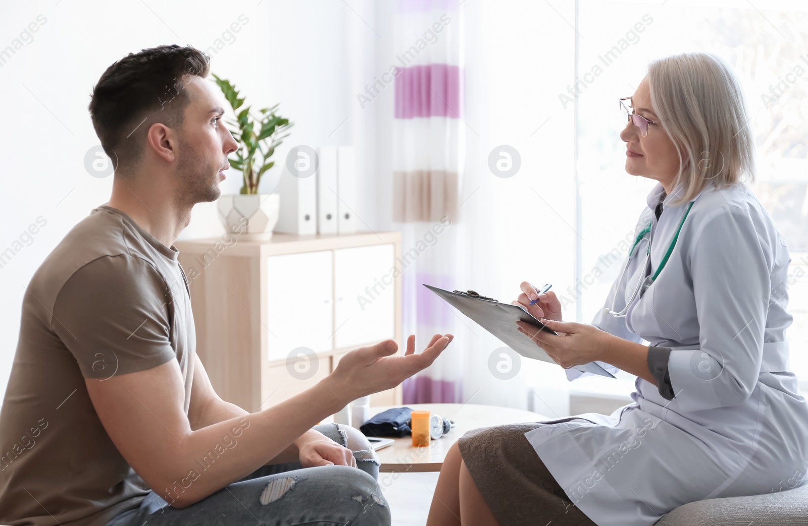 Photo of Mature doctor consulting patient at home