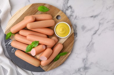 Photo of Delicious boiled sausages, sauce and basil on white marble table, top view. Space for text