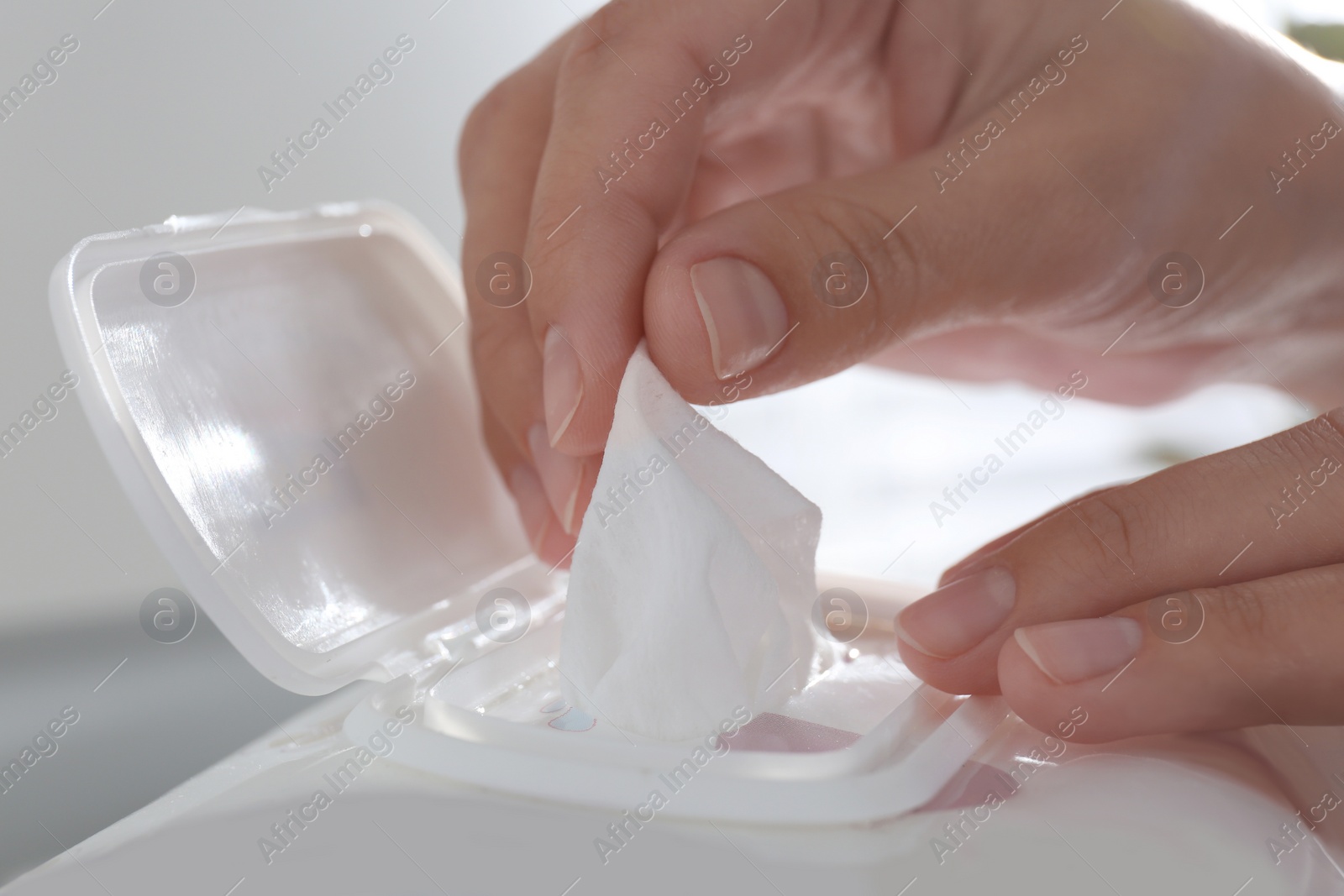 Photo of Woman taking wet wipe from pack on blurred background, closeup