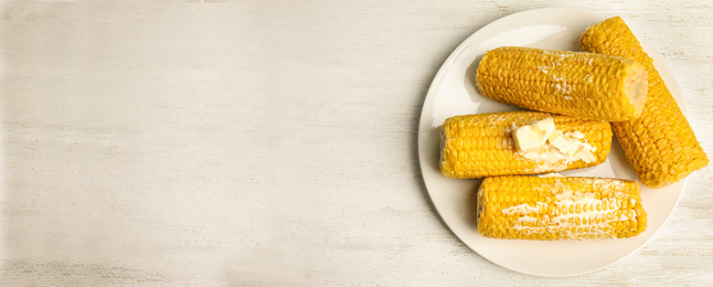 Delicious boiled corn with butter and space for text on white wooden table, top view. Banner design