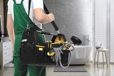 Plumber with bag of instruments in bathroom, closeup. Space for text