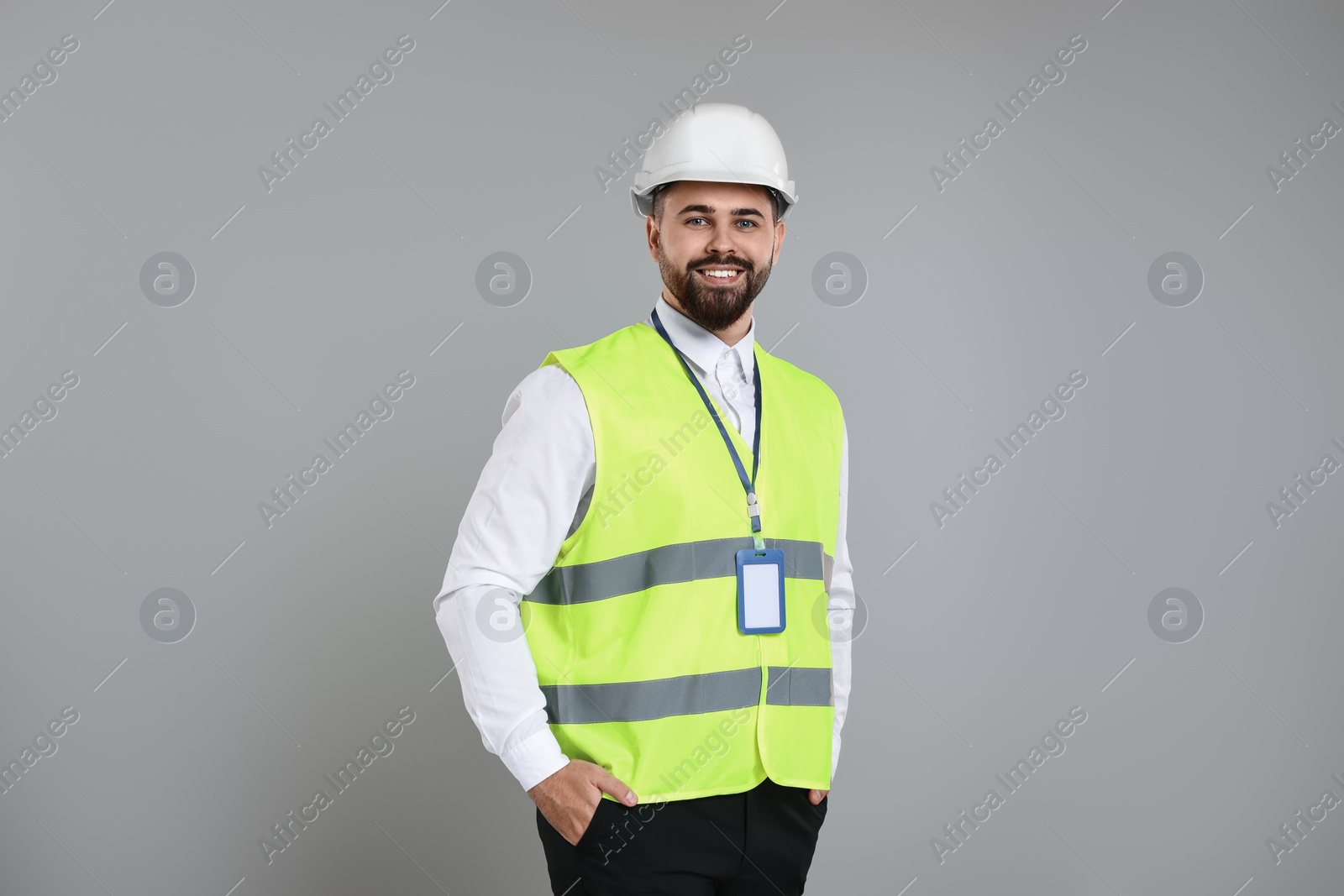 Photo of Engineer with hard hat and badge on grey background