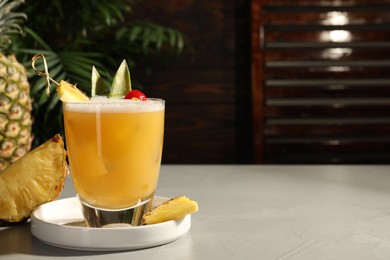 Photo of Tasty pineapple cocktail and fresh fruit on light grey table. Space for text