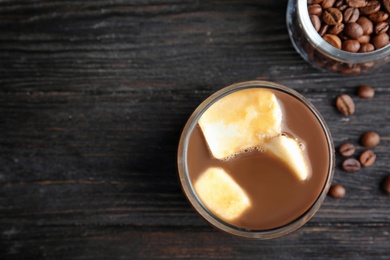 Photo of Coffee drink with milk ice cubes and beans on dark background, flat lay. Space for text