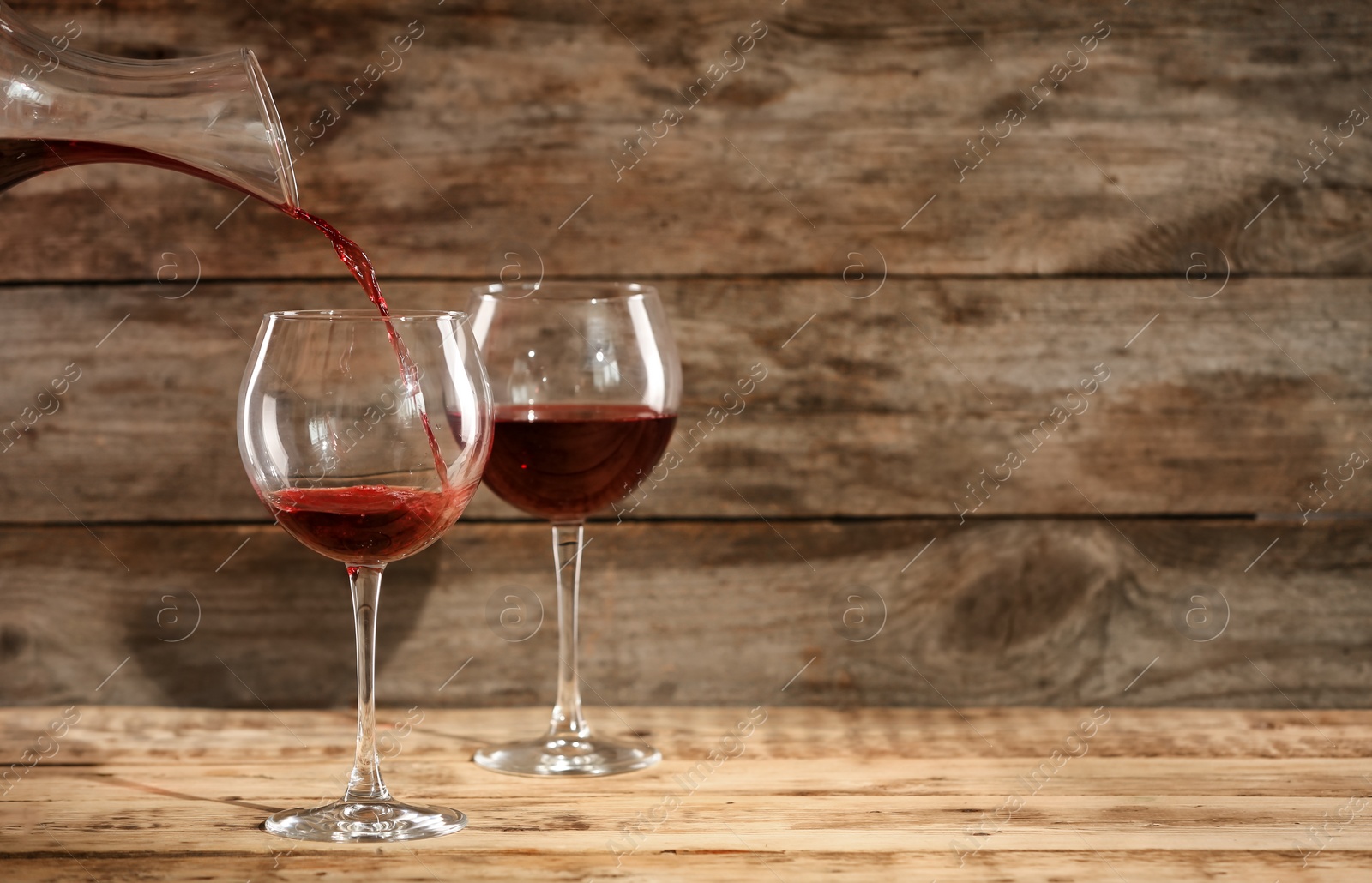 Photo of Pouring delicious red wine into glass on table