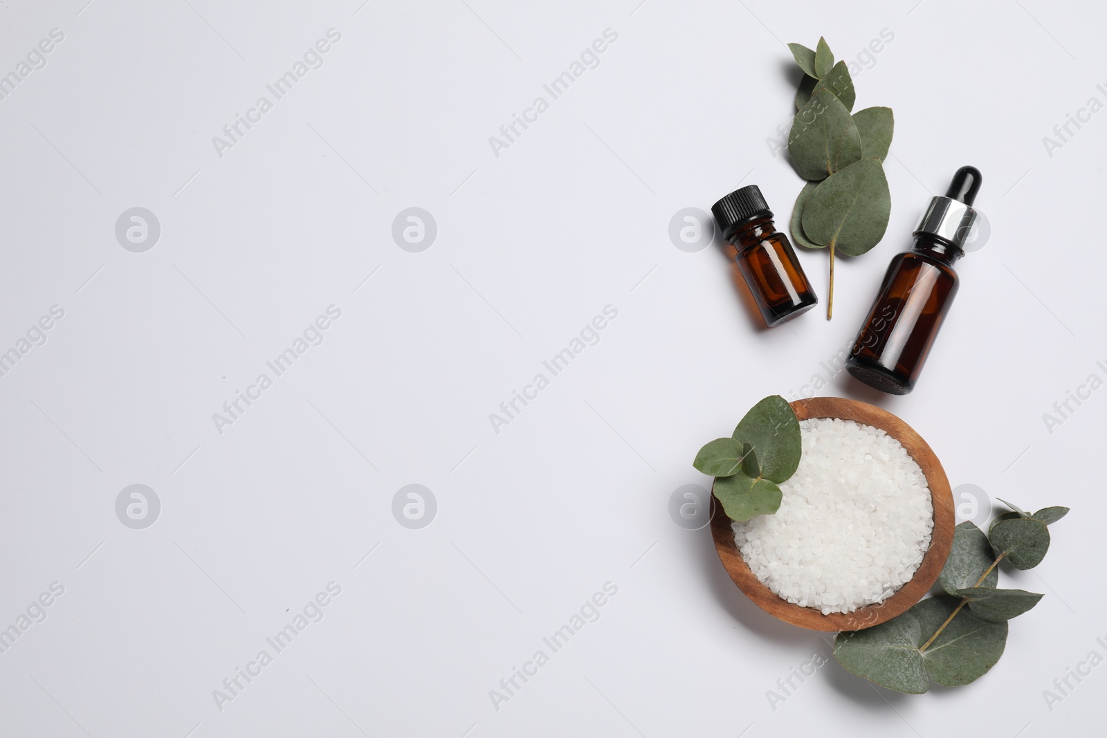 Photo of Aromatherapy products. Bottles of essential oil, sea salt and eucalyptus leaves on white background, flat lay. Space for text