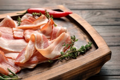 Photo of Board with raw bacon rashers on table, closeup