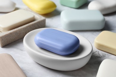Photo of Many different soap bars on white marble table, closeup