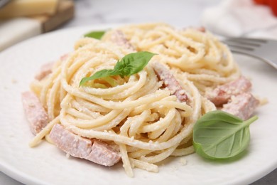 Photo of Tasty pasta Carbonara with basil leaves on plate, closeup