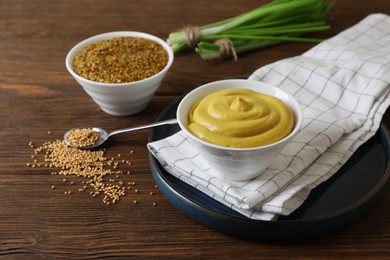 Photo of Delicious whole grain mustard, seeds and fresh green onion on wooden table