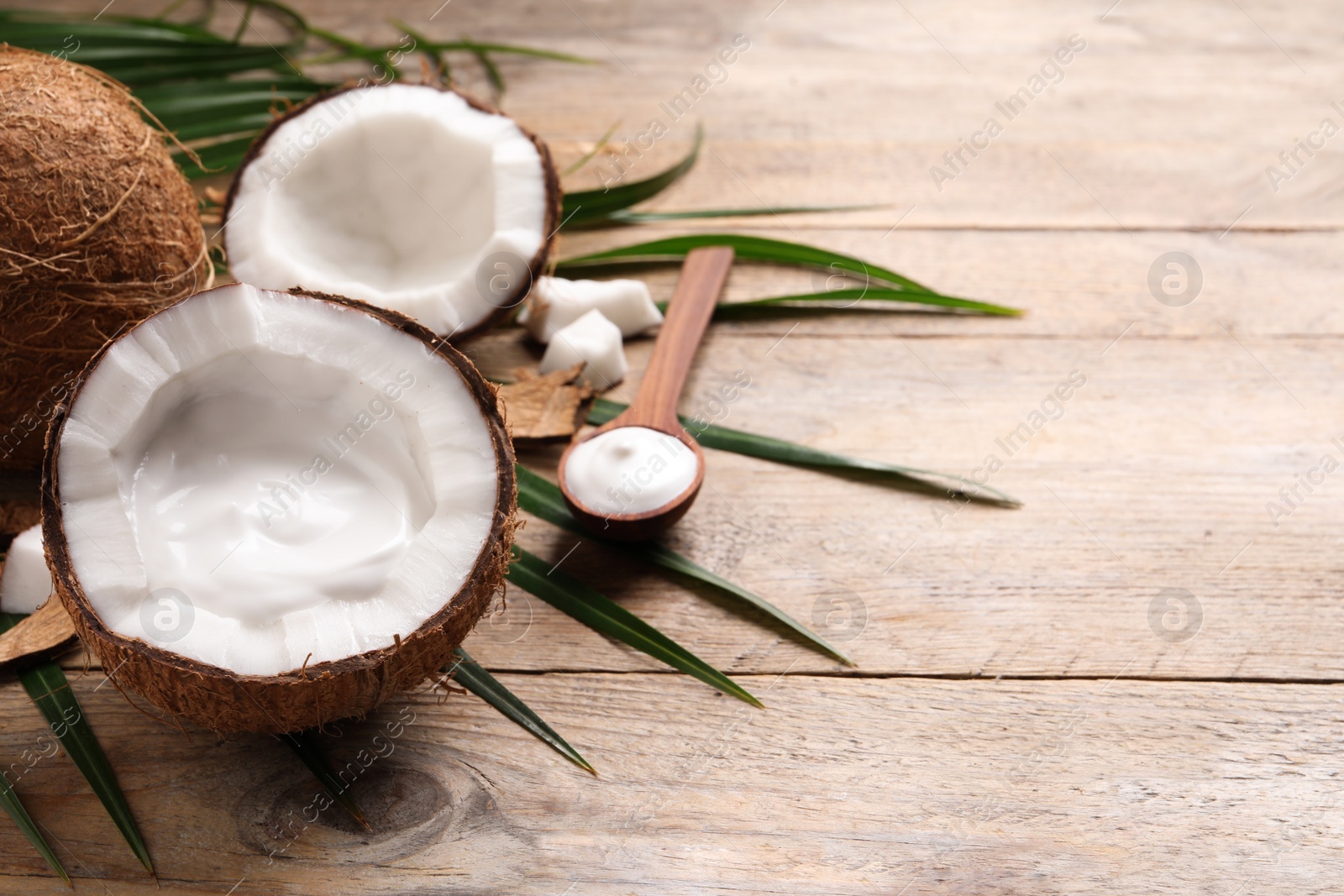 Photo of Ripe coconut and cream on wooden table. Space for text