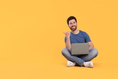 Photo of Happy man with laptop on yellow background. Space for text