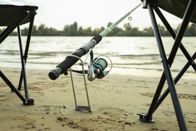 Photo of Fishing rod and folding chairs at riverside, closeup