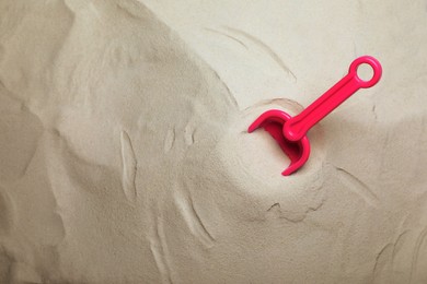 Photo of Bright plastic toy shovel on sand, top view