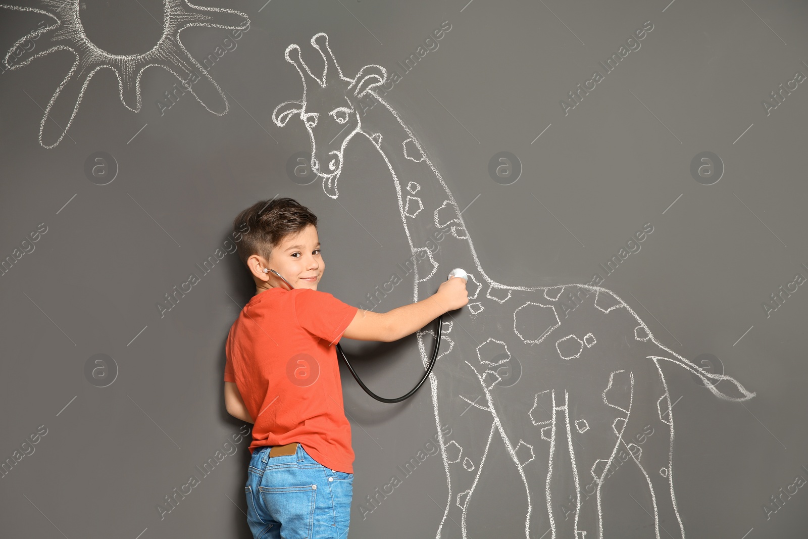 Photo of Cute little child playing doctor with chalk giraffe drawing on grey background