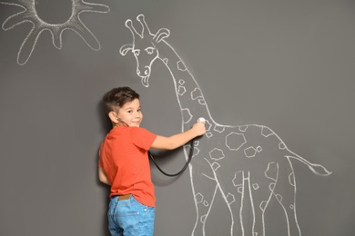 Cute little child playing doctor with chalk giraffe drawing on grey background