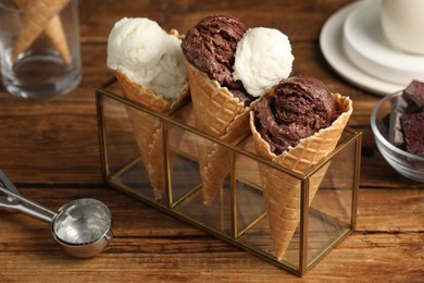 Tasty ice cream scoops in waffle cones on wooden table, closeup