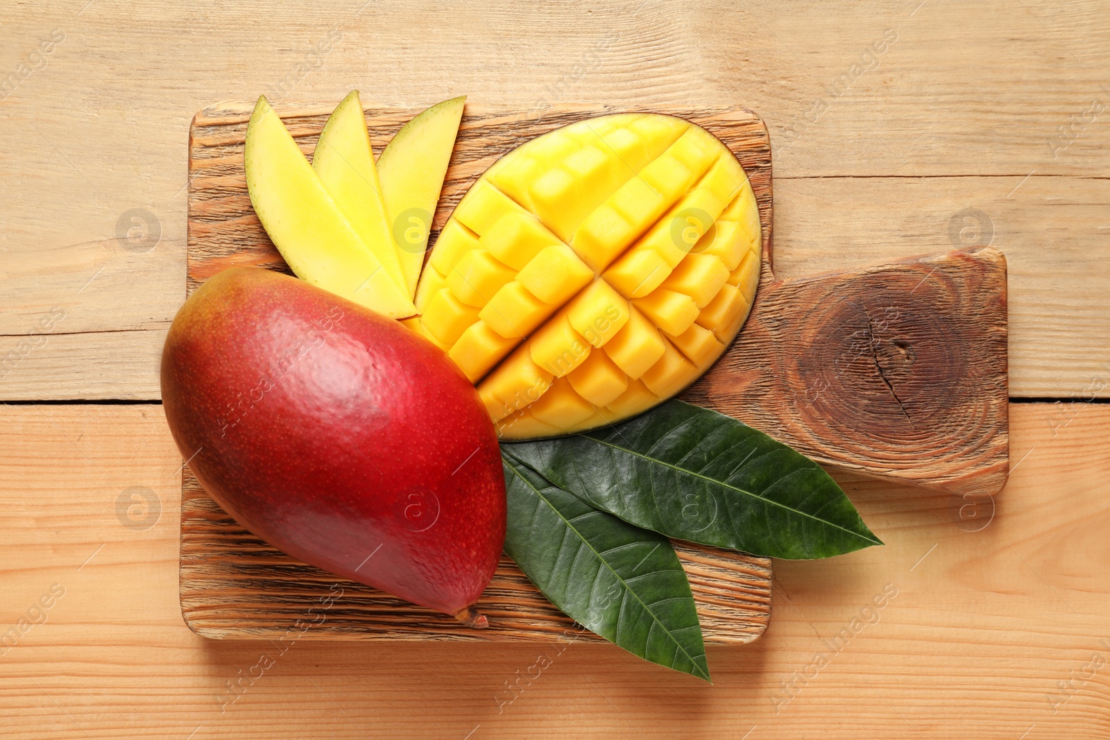 Photo of Board with fresh mango fruits on wooden background, top view