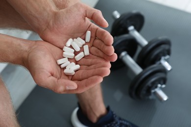 Photo of Man with handful of pills indoors, closeup. Doping concept