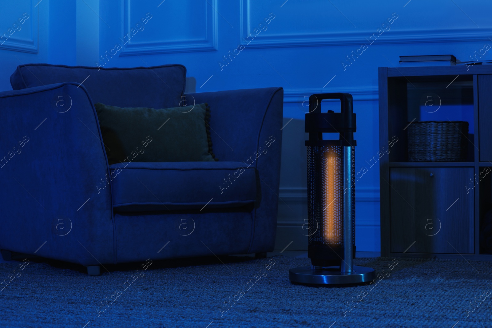 Photo of Electric infrared heater in dark living room at night