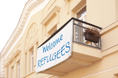 Image of Banner with phrase WELCOME REFUGEES on building outdoors