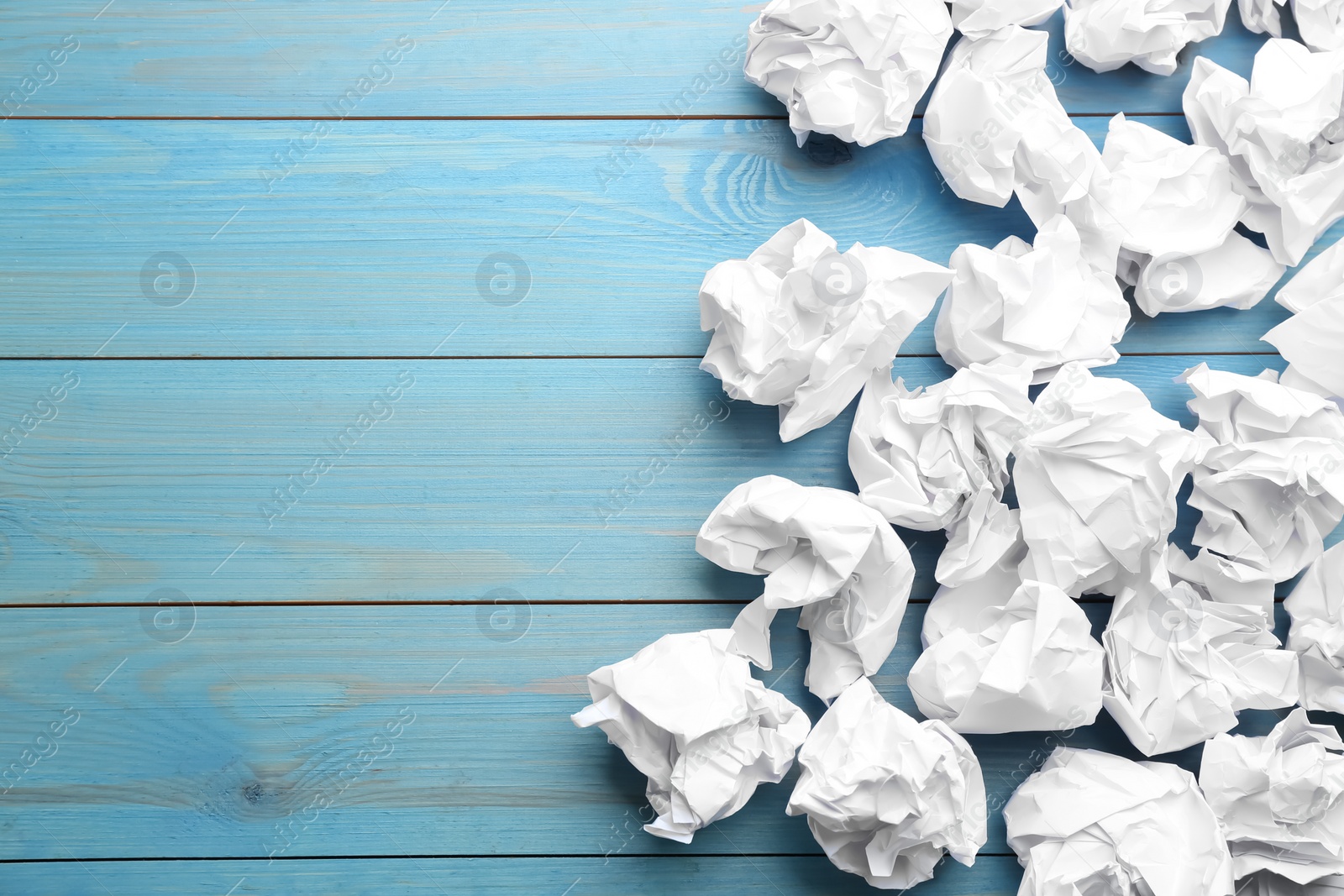 Photo of Crumpled sheets of paper on light blue wooden background, flat lay. Space for text