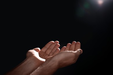 Photo of Man reaching hands to light in darkness, closeup