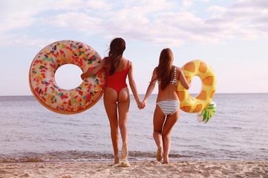 Young woman in bikini with girlfriend on beach. Lovely couple