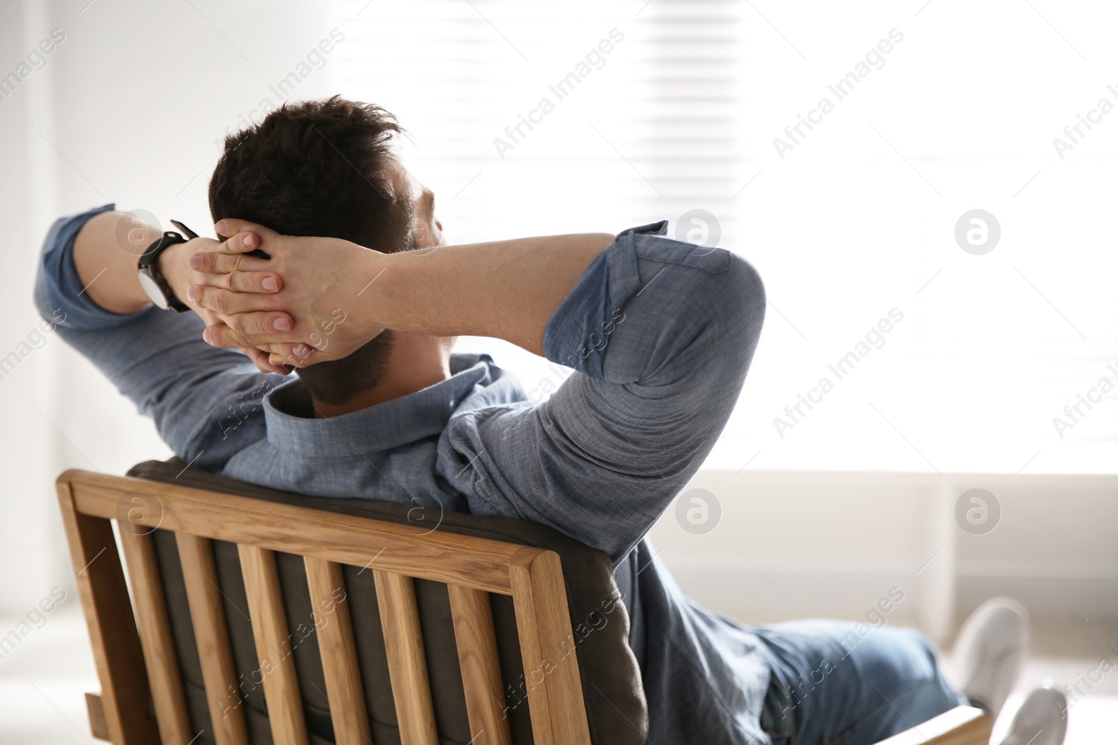 Photo of Young man relaxing in armchair near window at home