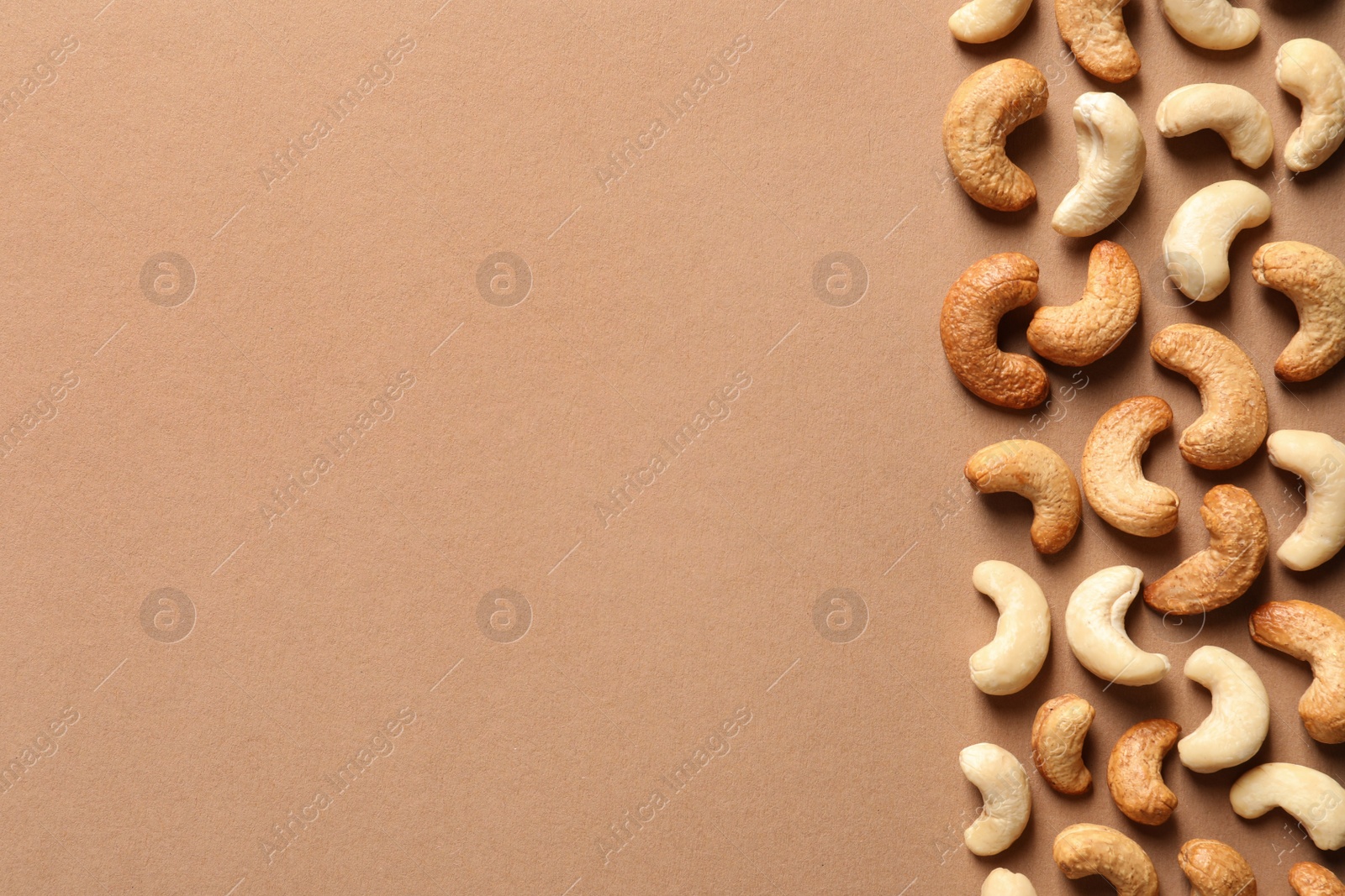 Photo of Tasty cashew nuts on color background, flat lay. Space for text