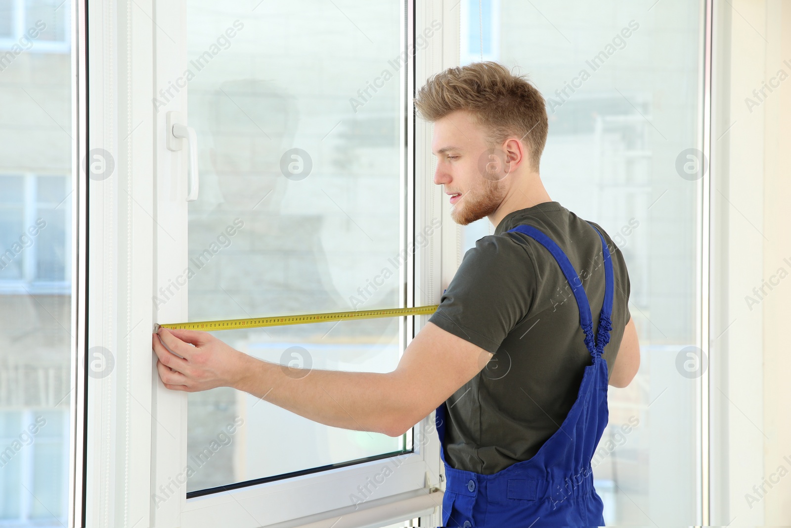 Photo of Service man measuring window for installation indoors