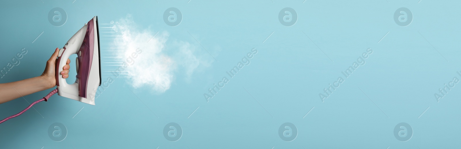 Image of Woman with iron on light blue background, closeup. Banner design with space for text