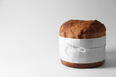 Delicious Panettone cake wrapped in parchment paper on white background. Traditional Italian pastry