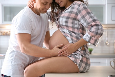 Pregnant woman with her husband in kitchen. Happy young family