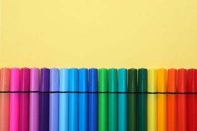 Photo of Many bright felt tip pens on light yellow background, flat lay. Space for text