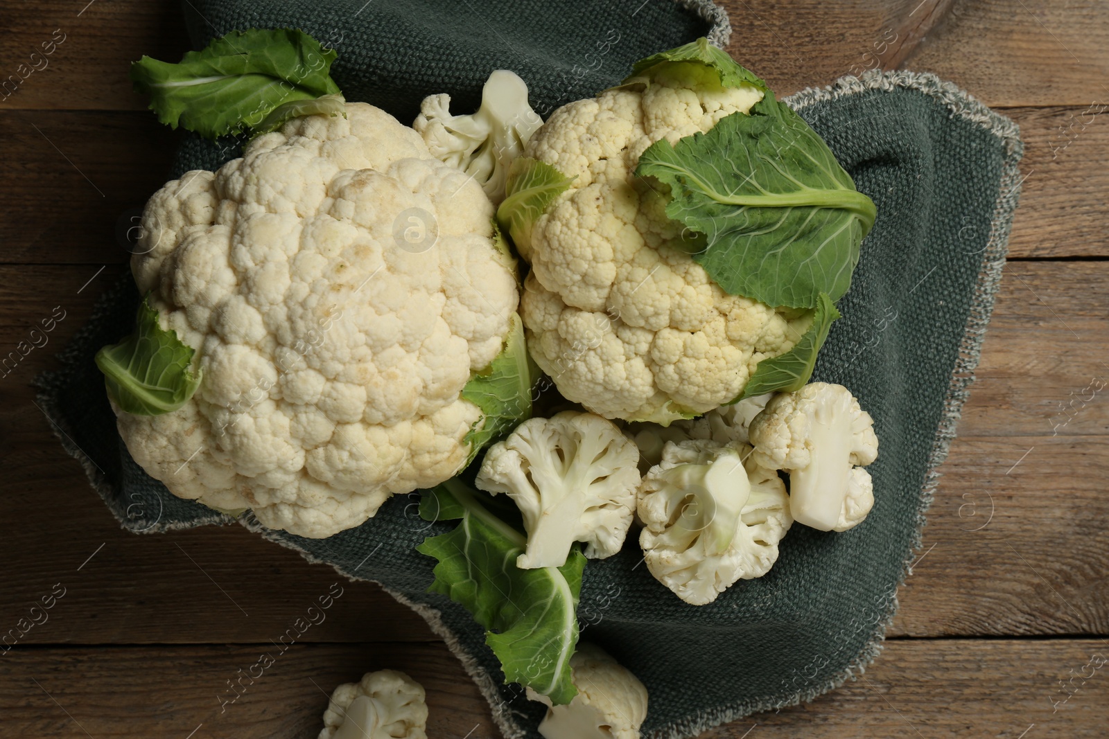 Photo of Cut and whole cauliflowers on wooden table, top view