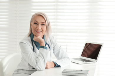 Portrait of mature female doctor in white coat at workplace