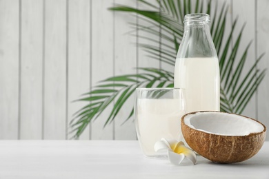 Photo of Composition with bottle and glass of coconut water on white wooden table. Space for text