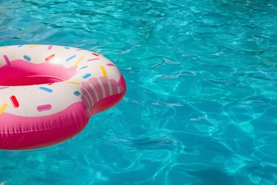 Photo of Inflatable ring floating in swimming pool on sunny day. Space for text